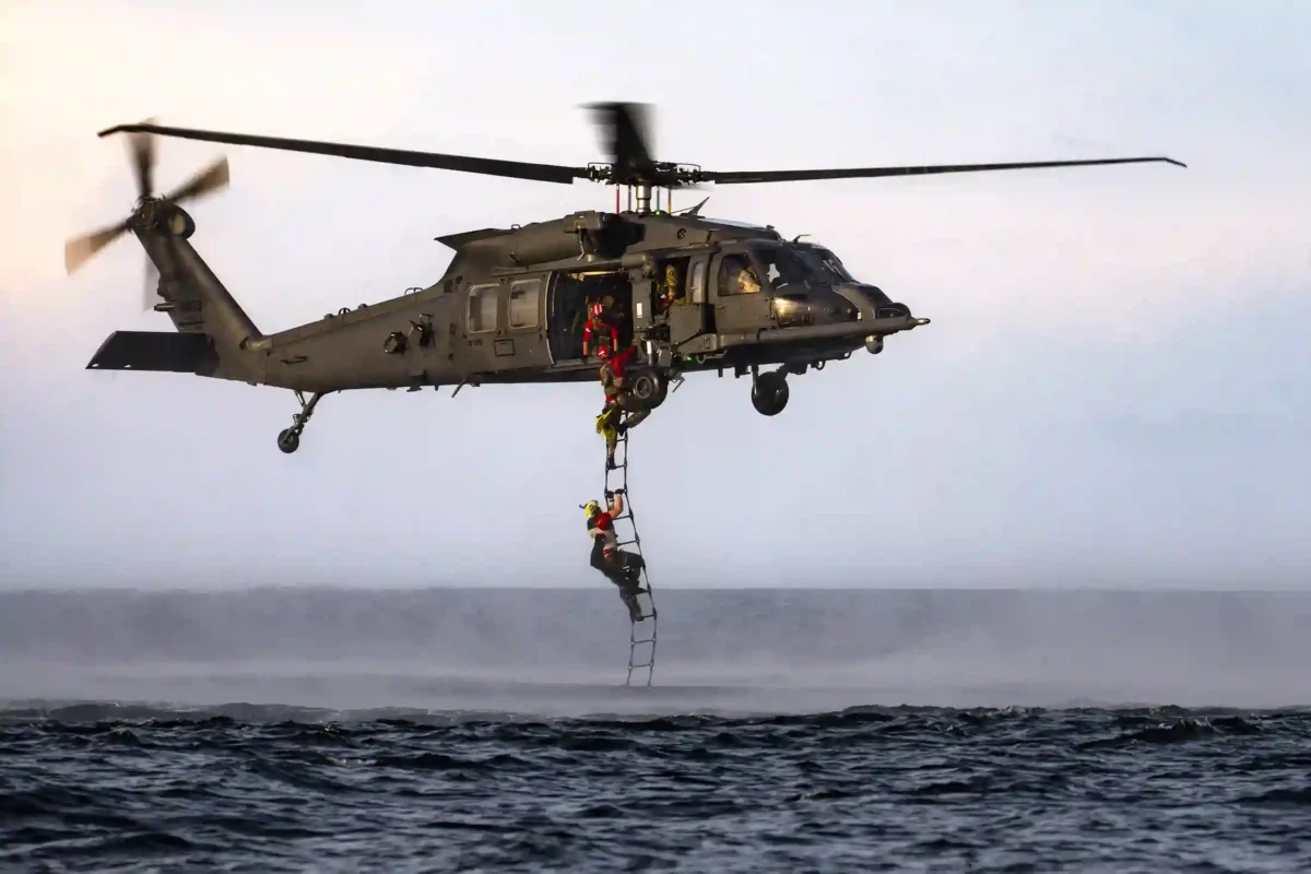 HH-60G Pave Hawk releasing flares with F-15D Eagle overhead during maritime trials.
