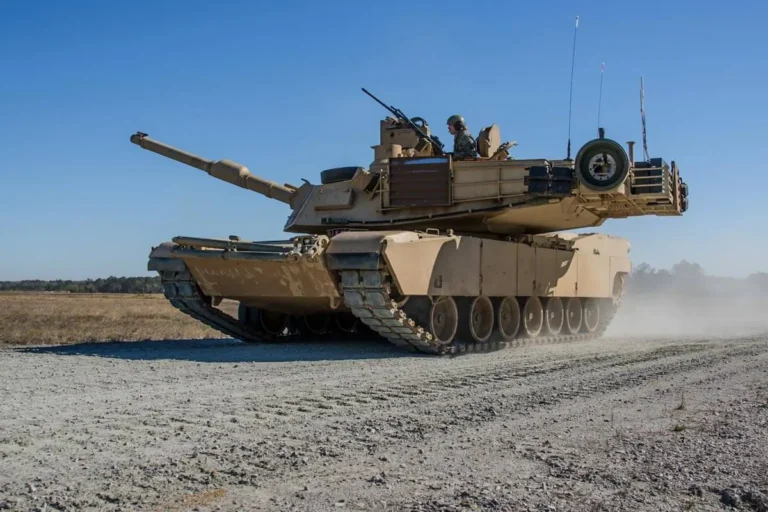 A U.S. Army M1A2 Abrams main battle tank moves along a dirt road during field training